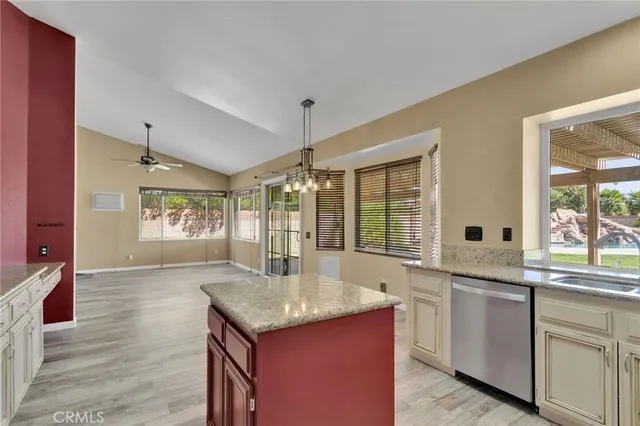 a large white kitchen with granite countertop a sink and dishwasher with wooden floor