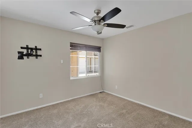 an empty room with a ceiling fan and window