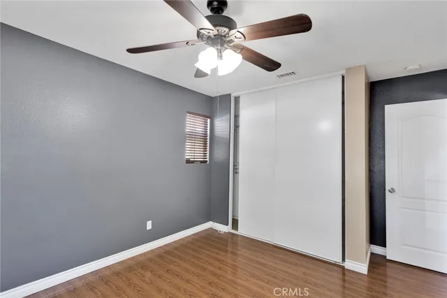 an empty room with wooden floor fan and windows