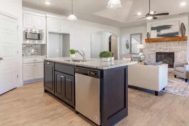 a kitchen with kitchen island granite countertop a sink cabinets and window