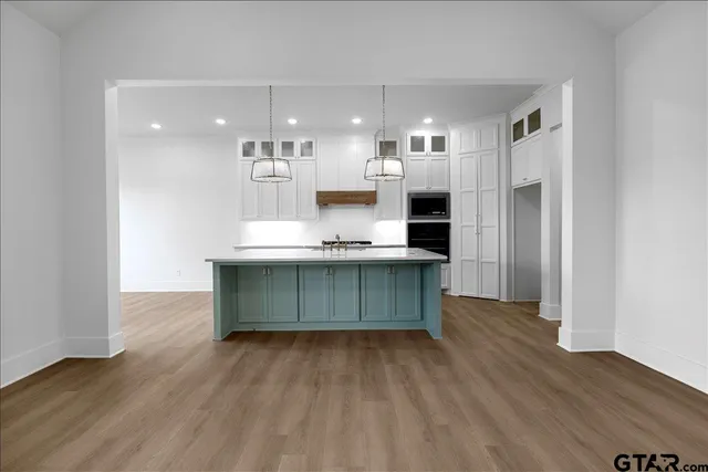a room with kitchen island a sink wooden floor and a large window