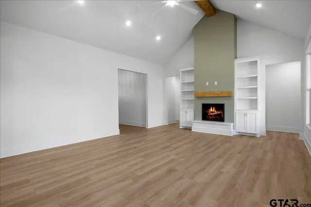 a view of an empty room with wooden floor fireplace and a window