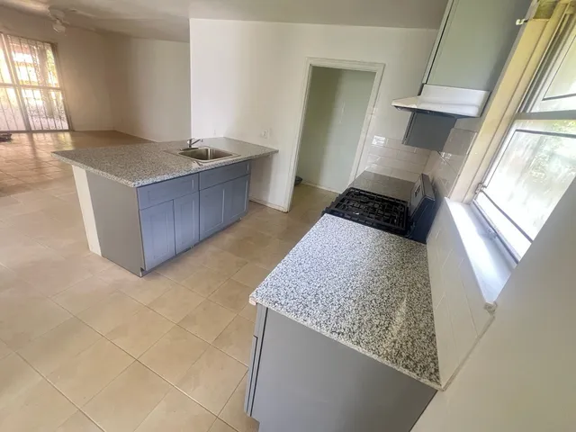a kitchen with granite countertop a sink a stove and a window