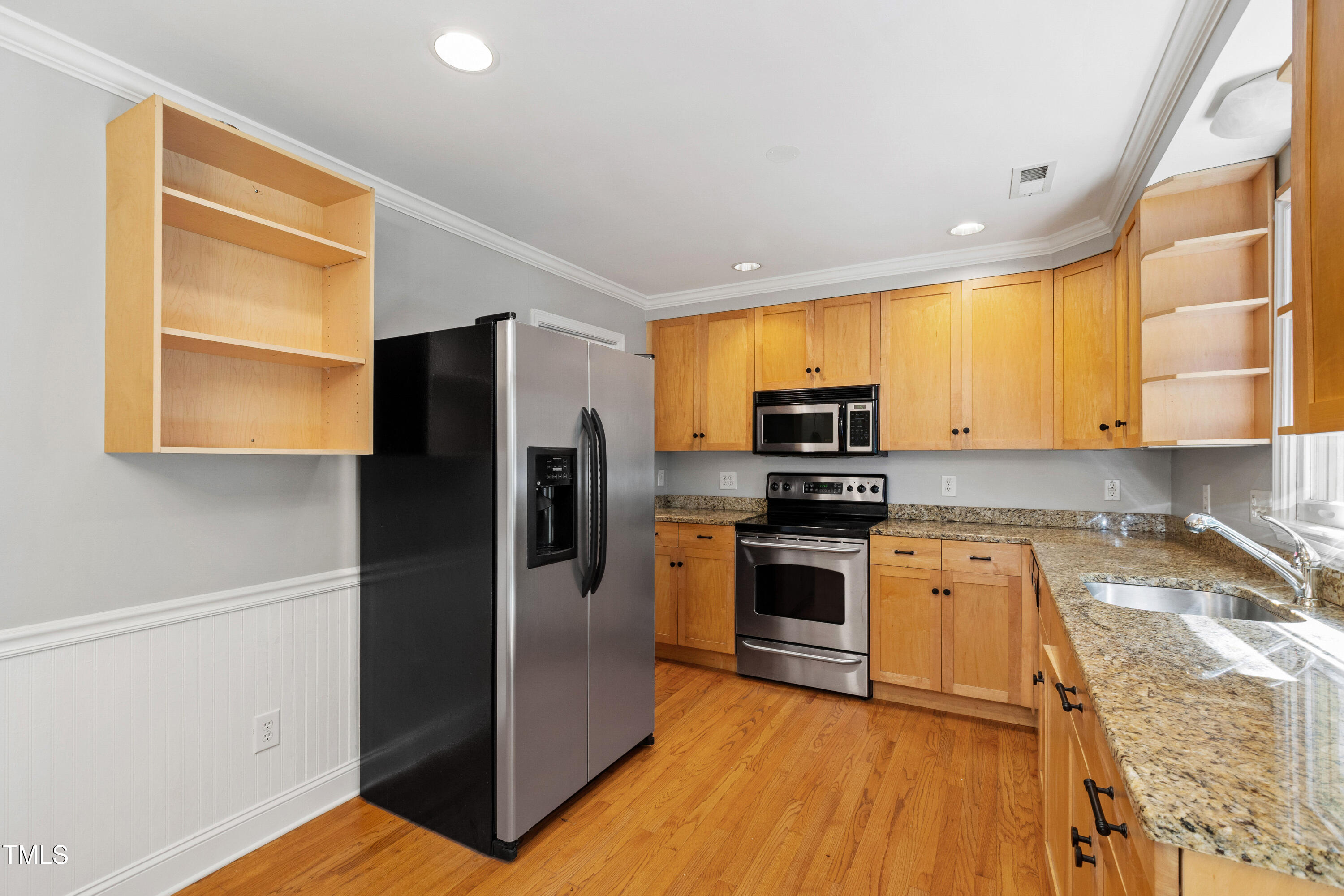 a kitchen with granite countertop a refrigerator and a stove top oven