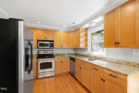 a kitchen with stainless steel appliances granite countertop a stove a sink and a refrigerator