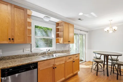 a kitchen with granite countertop a stove a sink and a wooden cabinets
