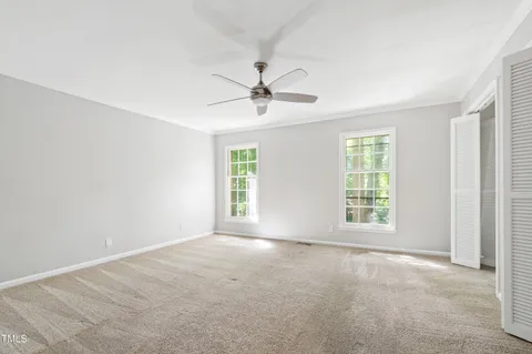 an empty room with windows and a ceiling fan