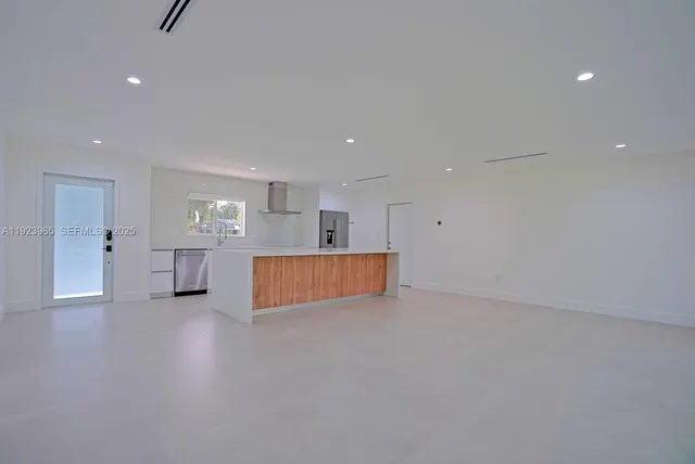a view of an empty room with wooden floor and windows