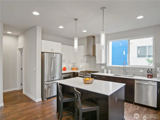 a kitchen that has a sink a center island stainless steel appliances and cabinets