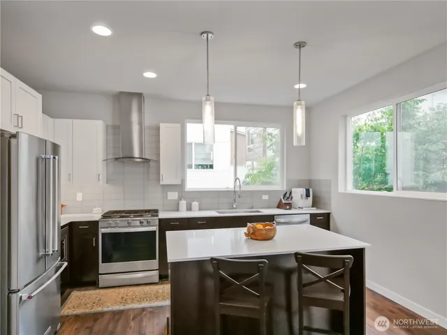 a kitchen with stainless steel appliances a stove a sink a microwave a refrigerator and white cabinets