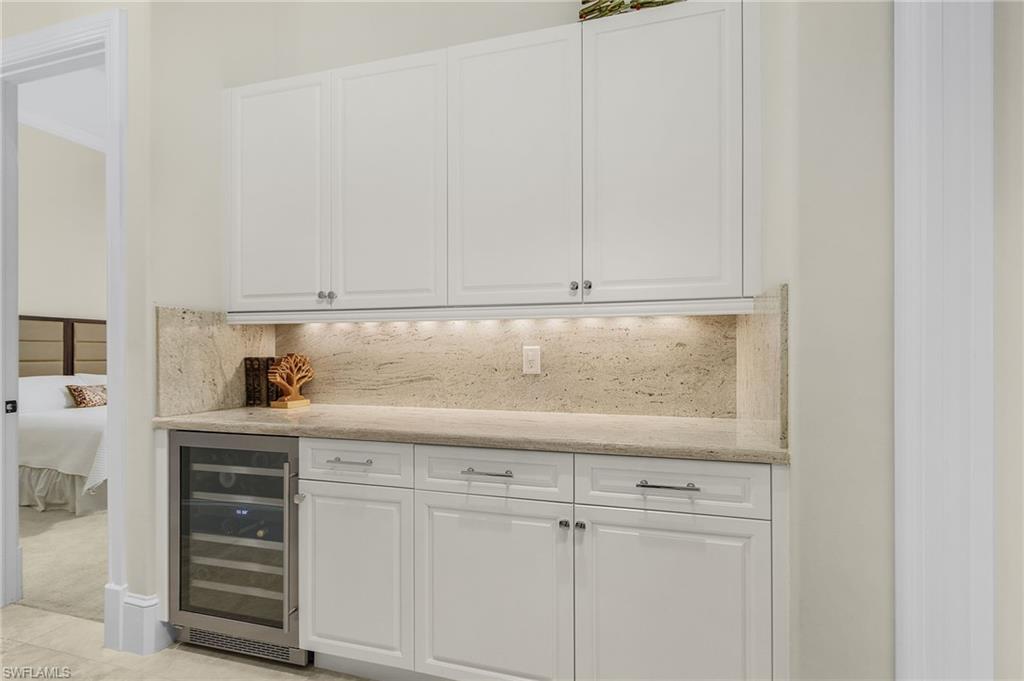2220 Residence Circle Naples, FL 34105 - Photo 11 of 50 Bar with white cabinets, beverage cooler, light stone counters, and tasteful backsplash