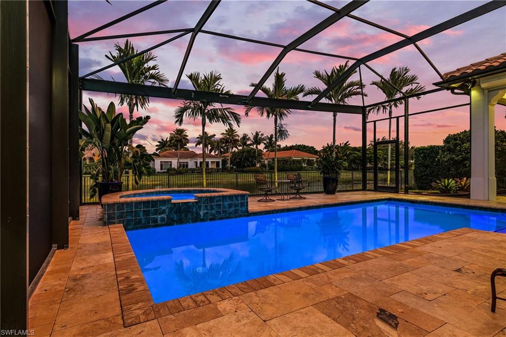 2220 Residence Circle Naples, FL 34105 - Photo 36 of 50 Pool at dusk featuring a pool with connected hot tub, a sunroom, glass enclosure, and a patio