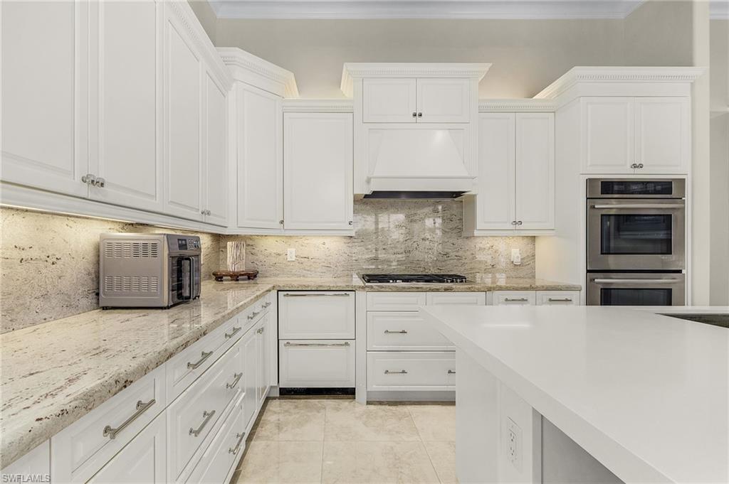 2220 Residence Circle Naples, FL 34105 - Photo 8 of 50 Kitchen featuring stainless steel double oven, tasteful backsplash, white cabinets, custom range hood, and ornamental molding