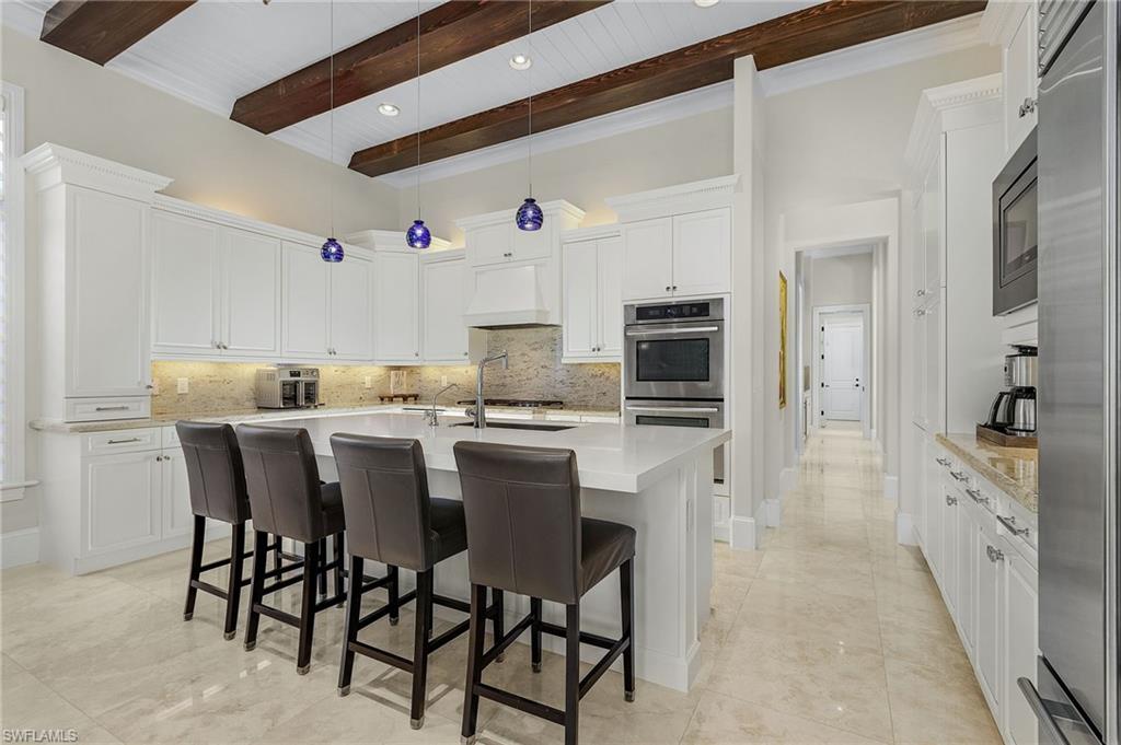 2220 Residence Circle Naples, FL 34105 - Photo 9 of 50 Kitchen featuring a breakfast bar, an island with sink, white cabinetry, tasteful backsplash, and built in appliances