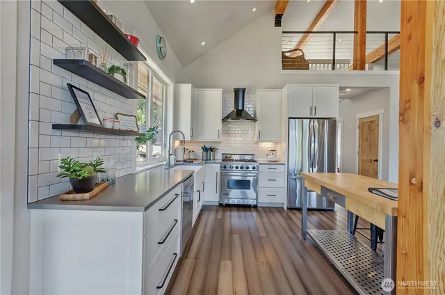 a kitchen with stainless steel appliances a lot of counter top space and wooden floor