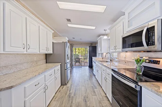 a large kitchen with stainless steel appliances granite countertop a lot of counter space and wooden floors