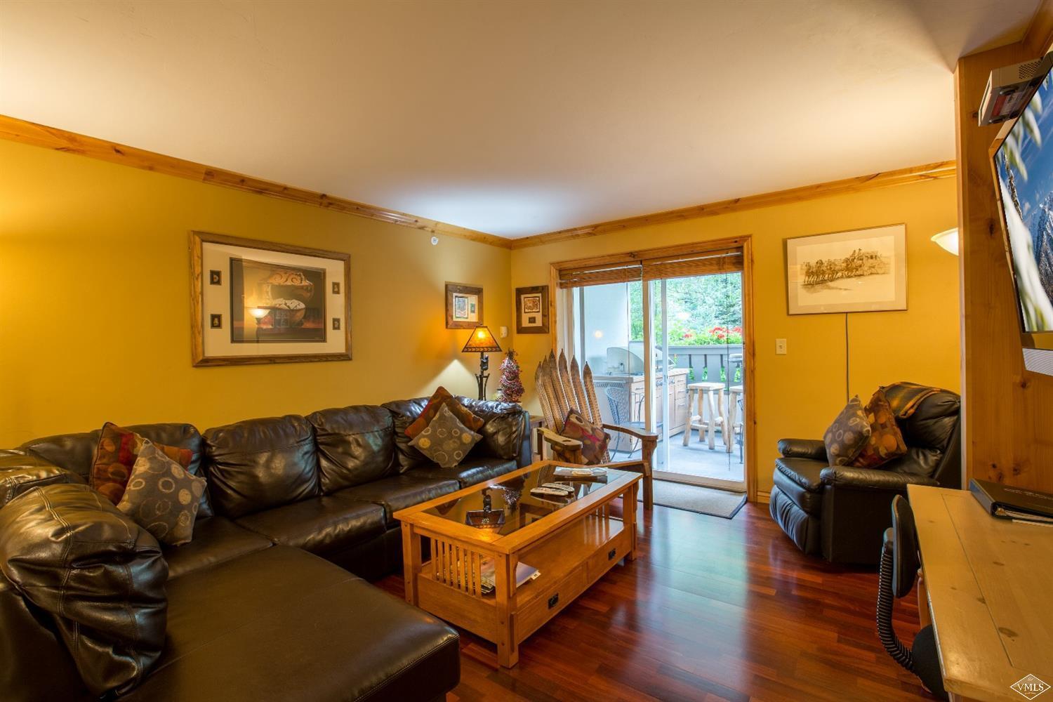 9 Vail Road, Unit 1J Vail, CO 81657 - Photo 3 of 14 a living room with furniture a flat screen tv and wooden floor