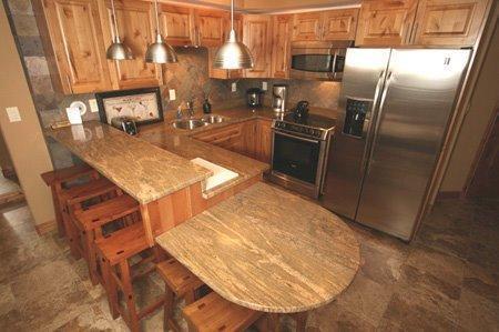 9 Vail Road, Unit 1J Vail, CO 81657 - Photo 4 of 14 an open kitchen with stainless steel appliances granite countertop a sink refrigerator and cabinets