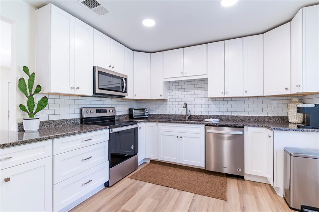 1344 Springdale Street Clearwater, FL 33755 - Photo 13 of 34 a kitchen with stainless steel appliances granite countertop white cabinets a stove a sink and a potted plant