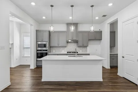 a view of a kitchen with kitchen island a counter top space stainless steel appliances and wooden floor