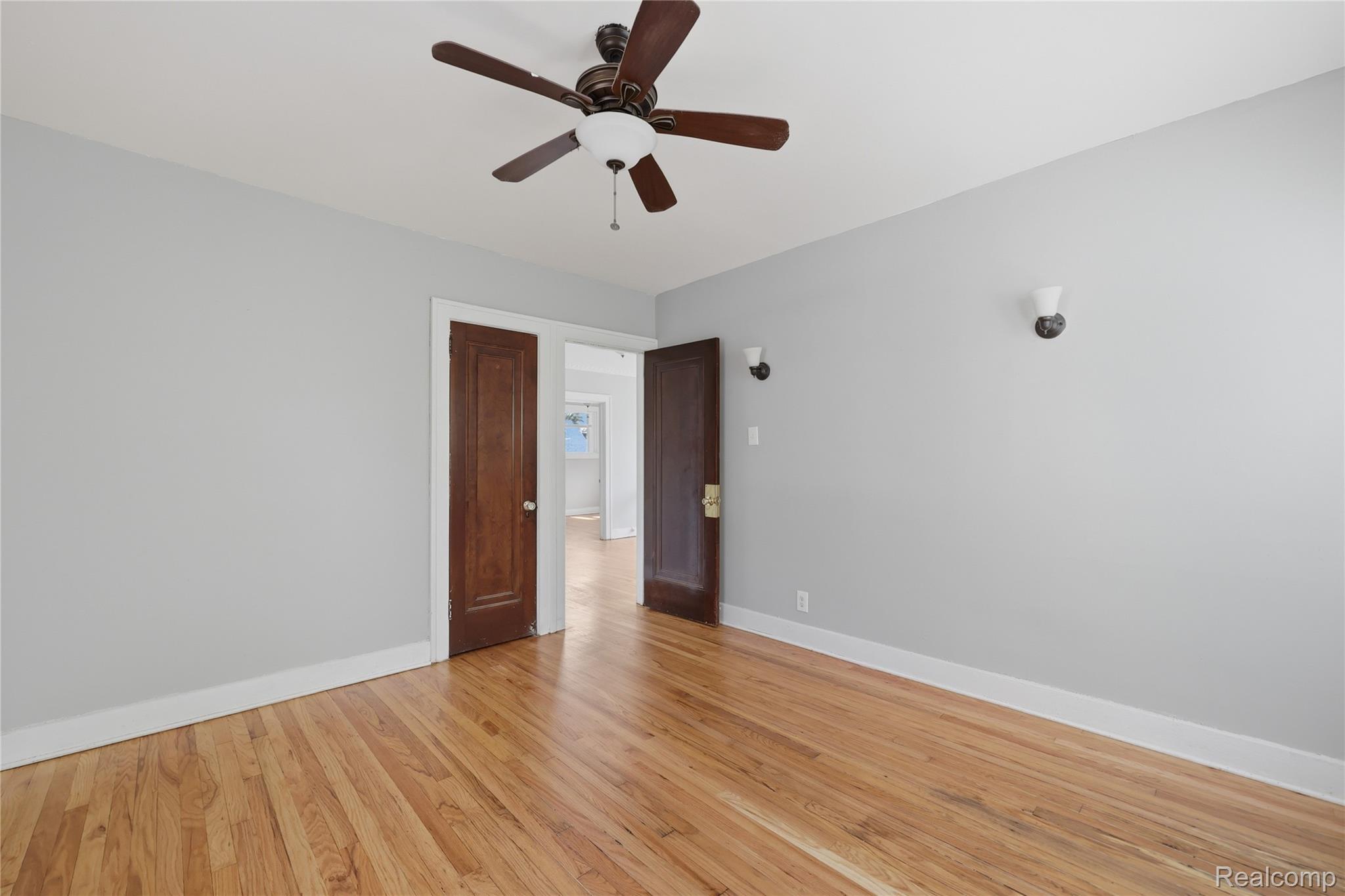 1945 Atkinson Street Detroit, MI 48206 - Photo 32 of 49 Spacious room featuring wood-finish flooring, light gray walls, white baseboards, a ceiling fan with integrated lighting, and two wall-mounted sconces