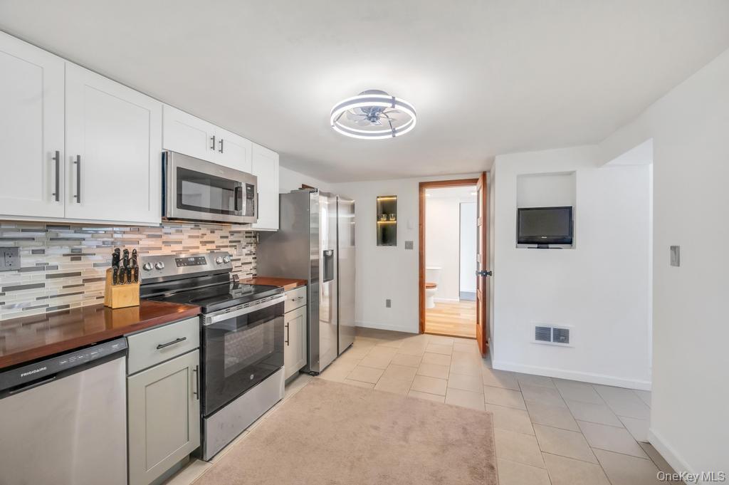 5 Panther Path Miller Place, NY 11764 - Photo 15 of 37 Kitchen with stainless steel appliances, wooden counters, tasteful backsplash, light tile patterned floors, and white cabinetry
