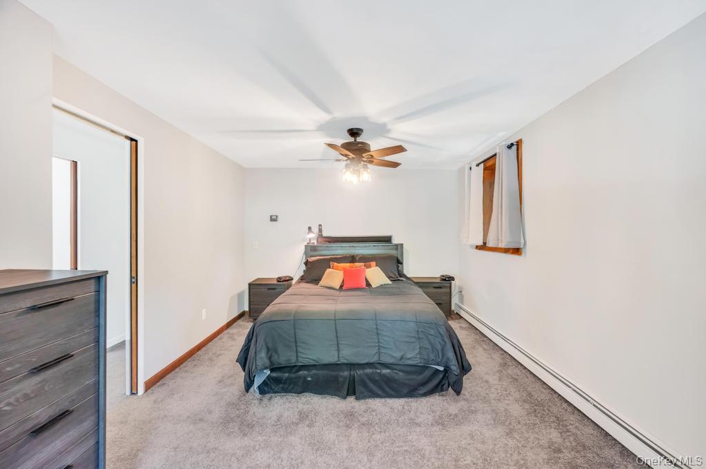 5 Panther Path Miller Place, NY 11764 - Photo 21 of 37 Bedroom featuring a baseboard heating unit, light carpet, and ceiling fan
