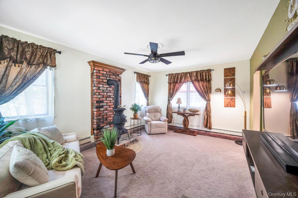 5 Panther Path Miller Place, NY 11764 - Photo 29 of 37 Living area featuring a wood stove, carpet, ceiling fan, and baseboard heating