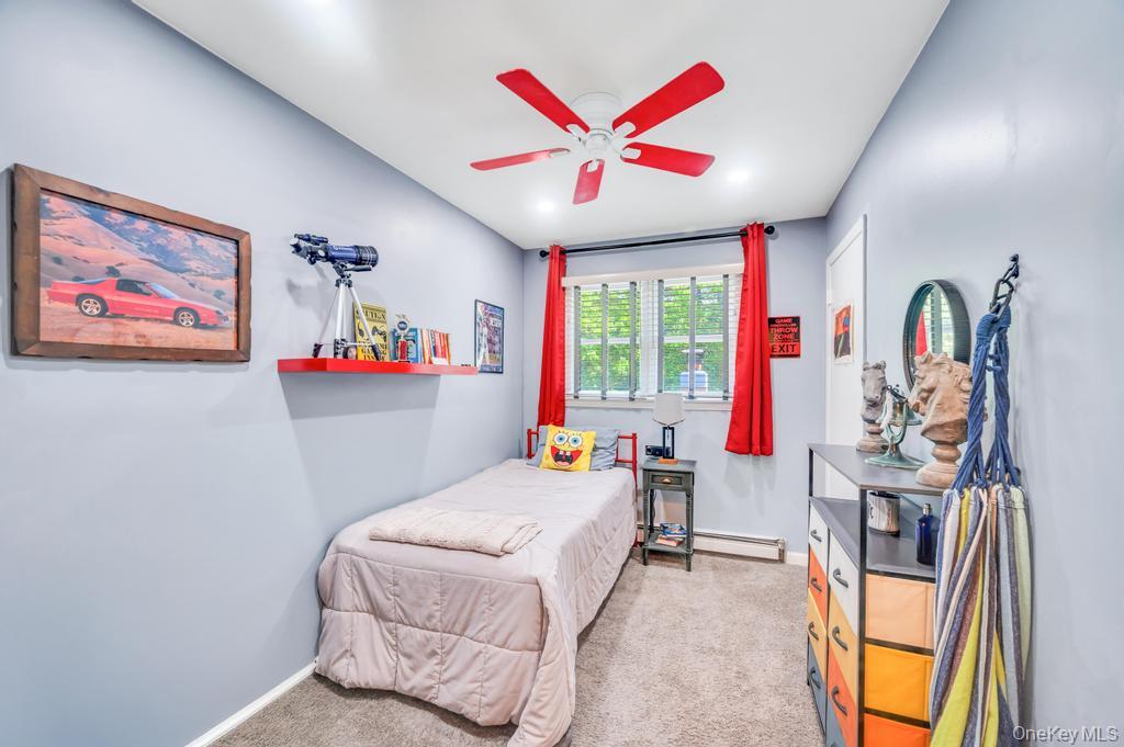 5 Panther Path Miller Place, NY 11764 - Photo 32 of 37 Bedroom with light colored carpet, a ceiling fan, and a baseboard heating unit