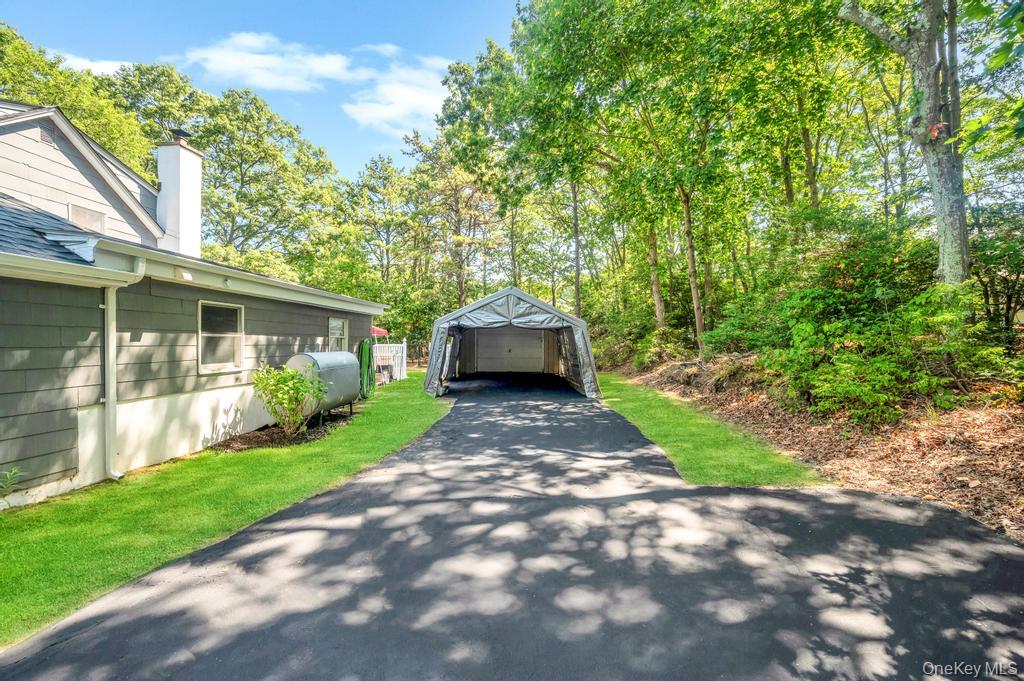 5 Panther Path Miller Place, NY 11764 - Photo 5 of 37 View of home's exterior with an outbuilding, a detached garage, a chimney, oil tank, and a shingled roof