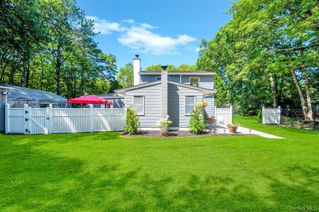 5 Panther Path Miller Place, NY 11764 - Photo 9 of 37 Back of property with a gate, a chimney, and view of scattered trees