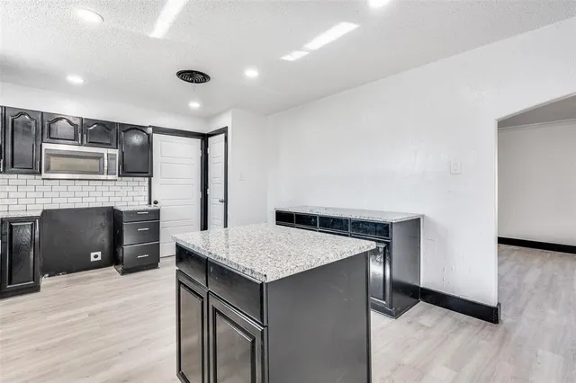 a kitchen with kitchen island a counter top space a sink stainless steel appliances and cabinets