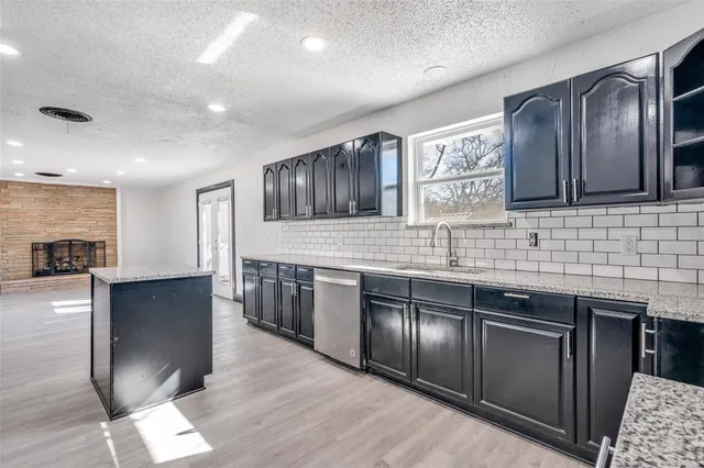a kitchen with stainless steel appliances granite countertop a refrigerator a sink and wooden cabinets