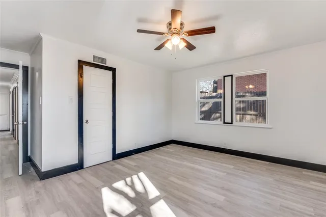 a view of an empty room with a window and wooden floor