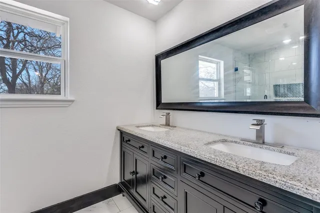 a bathroom with a granite countertop sink two large mirror and a window