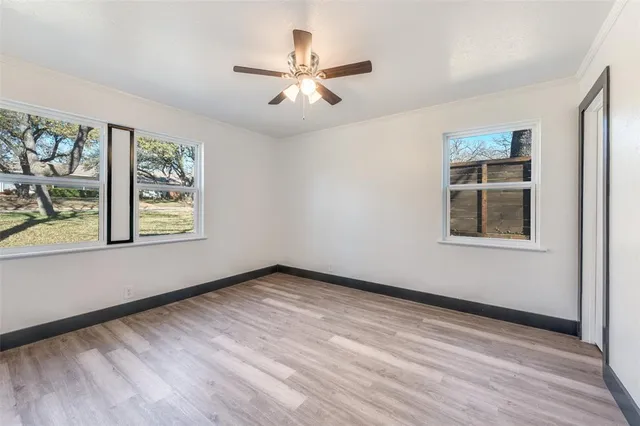 a view of an empty room with a window and wooden floor