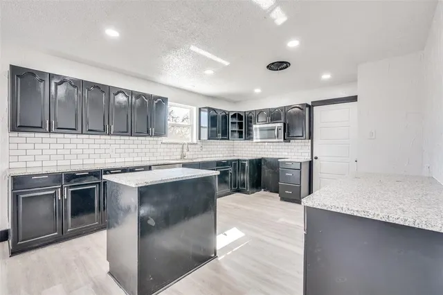 a large kitchen with stainless steel appliances kitchen island a large counter top and a sink
