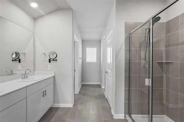 a spacious bathroom with a double vanity sink a large mirror a shower and a glass door