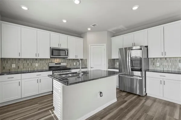 a kitchen with granite countertop a sink stove and refrigerator