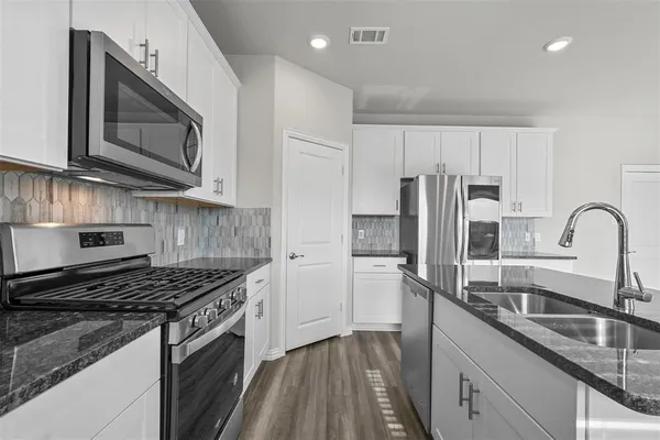 a kitchen with stainless steel appliances granite countertop a sink stove and refrigerator