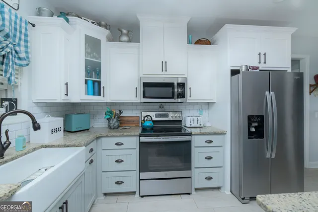 a kitchen with white cabinets and stainless steel appliances