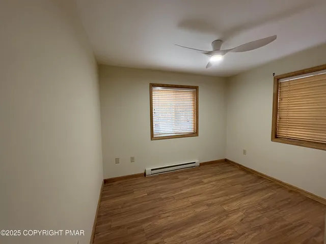 an empty room with wooden floor and windows