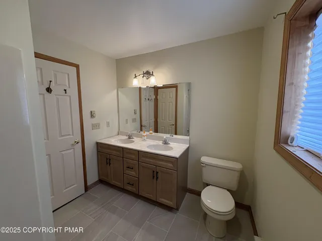 a bathroom with a toilet sink vanity granite and shower