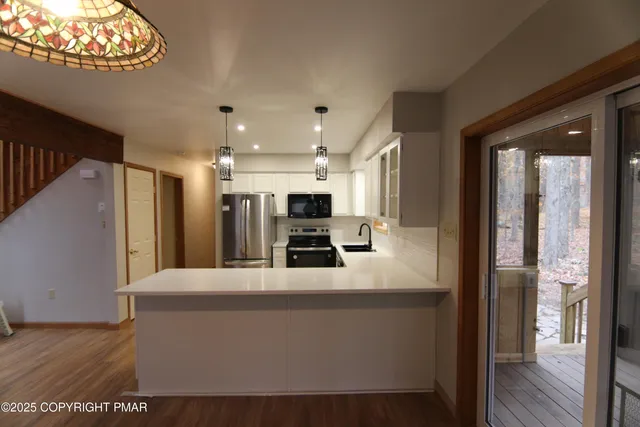 a large white kitchen with a large window and stainless steel appliances