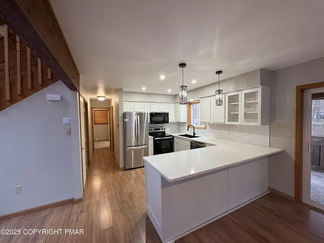 a large white kitchen with wooden floor and a sink