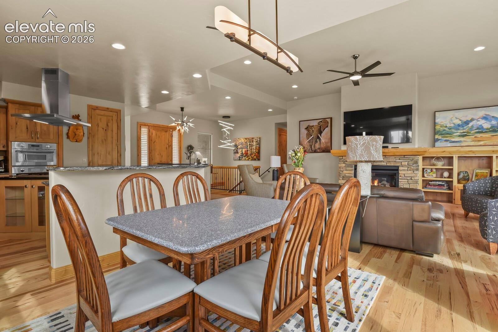 5545 Wilson Road Colorado Springs, CO 80919 - Photo 15 of 48 Open-concept living area featuring a stone-faced fireplace, built-in shelving, wood-finish flooring, and recessed lighting