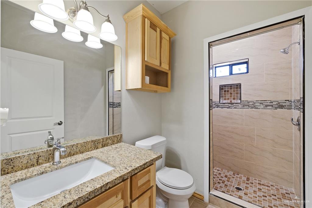 9445 Mile 20 Road Edcouch, TX 78538 - Photo 13 of 24 a bathroom with a granite countertop sink a toilet and a mirror