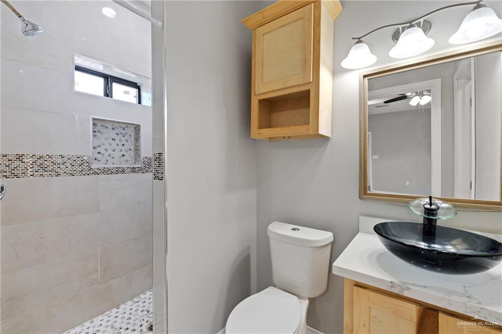 9445 Mile 20 Road Edcouch, TX 78538 - Photo 15 of 24 a bathroom with a granite countertop sink a toilet and a mirror