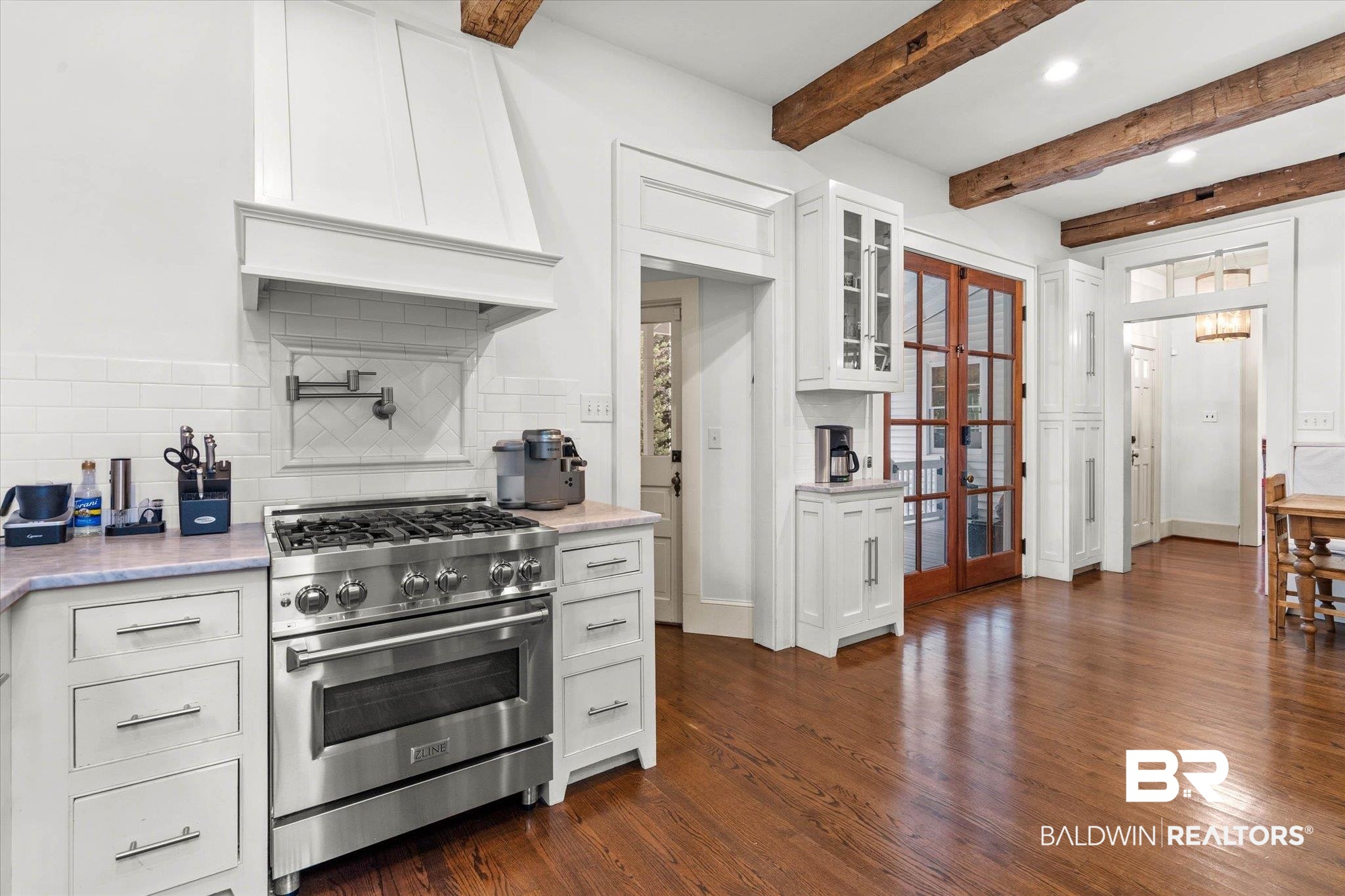 3863 Old Shell Road Mobile, AL 36608 - Photo 12 of 48 Gourmet kitchen featuring a stainless steel range with a pot filler, white shaker cabinetry, hardwood flooring, exposed wood beams, and French doors