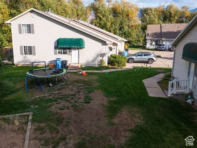 190 West 700 North Logan, UT 84321 - Photo 20 of 51 View of green lawn with a trampoline and view of scattered trees